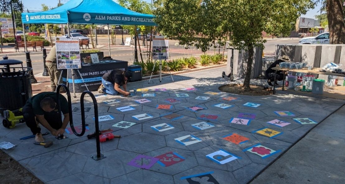 An A&M Parks and Recreation tent at a community event with stencils laid out