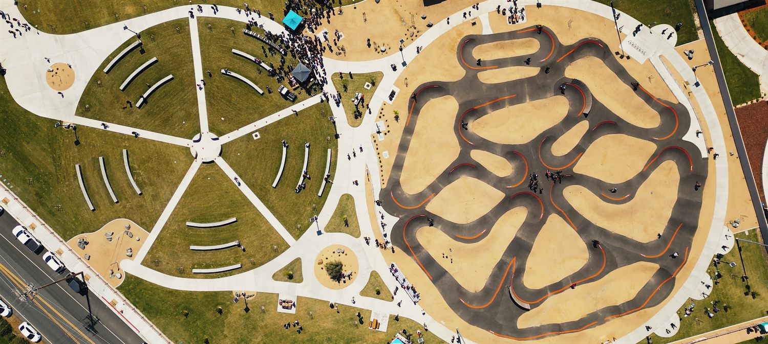 Aerial view of a new community park with amphitheater and bike pump track on opening day